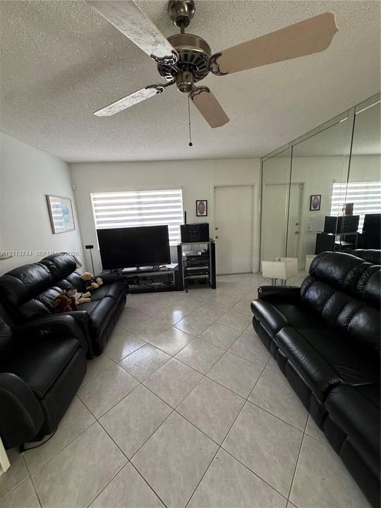 Ceramic tile flooring, full-wall mirrored closet doors, ceiling fan with light fixture, and dual-layered window shades