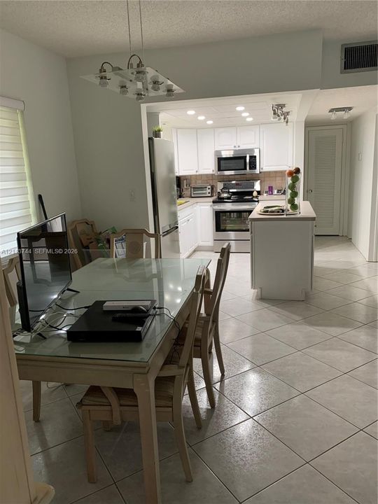 Kitchen featuring white cabinetry, stainless steel appliances, an integrated island, recessed lighting, and tile flooring