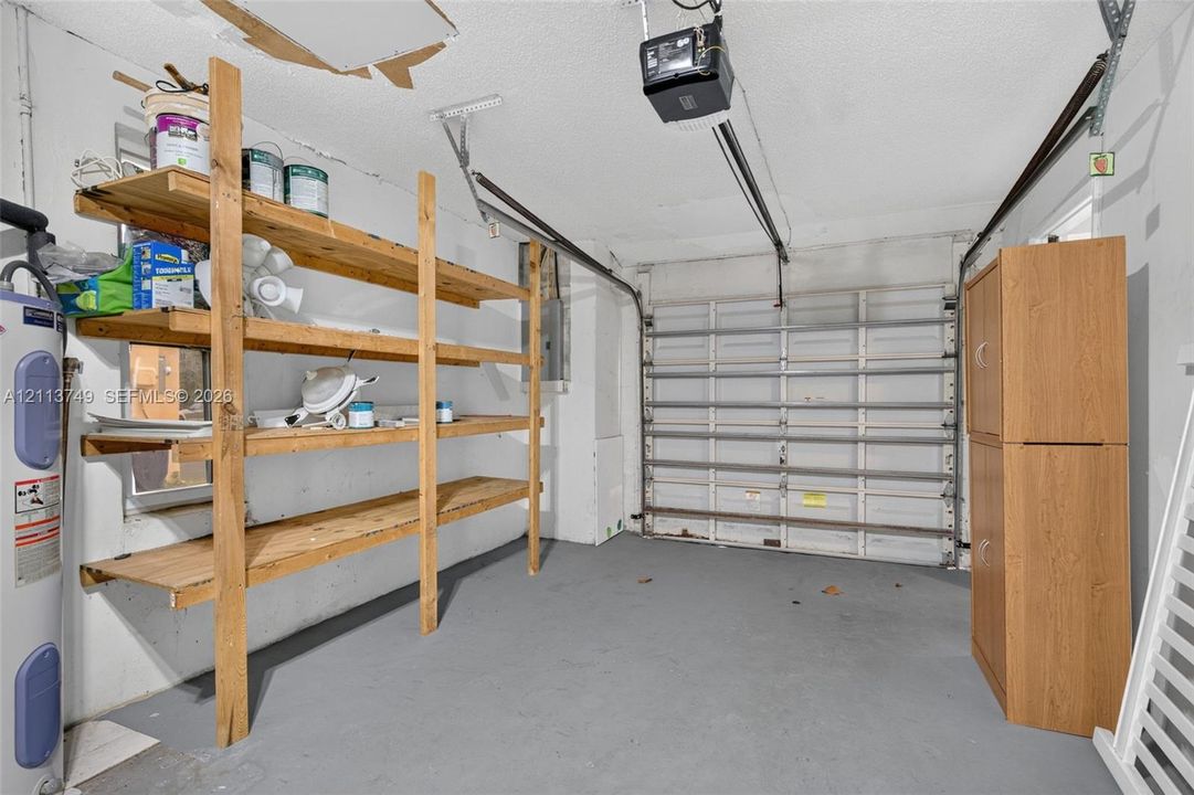 Enclosed garage featuring a sectional overhead door, painted concrete flooring, and built-in wood shelving