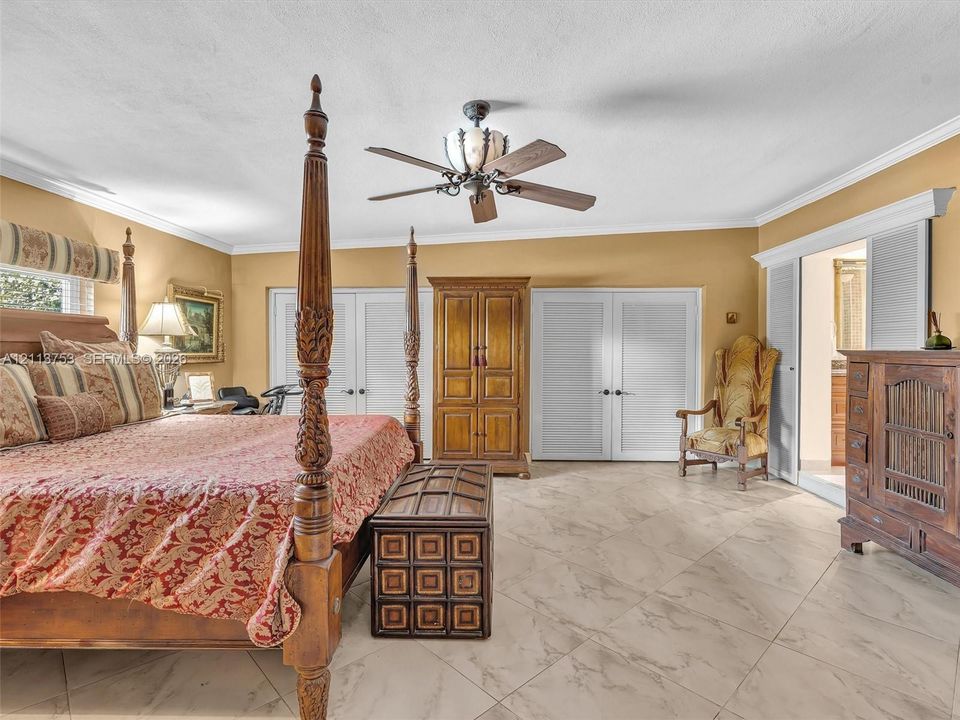 Large-format tile flooring, crown molding, multi-panel louvered doors, and a decorative ceiling fan with integrated lighting