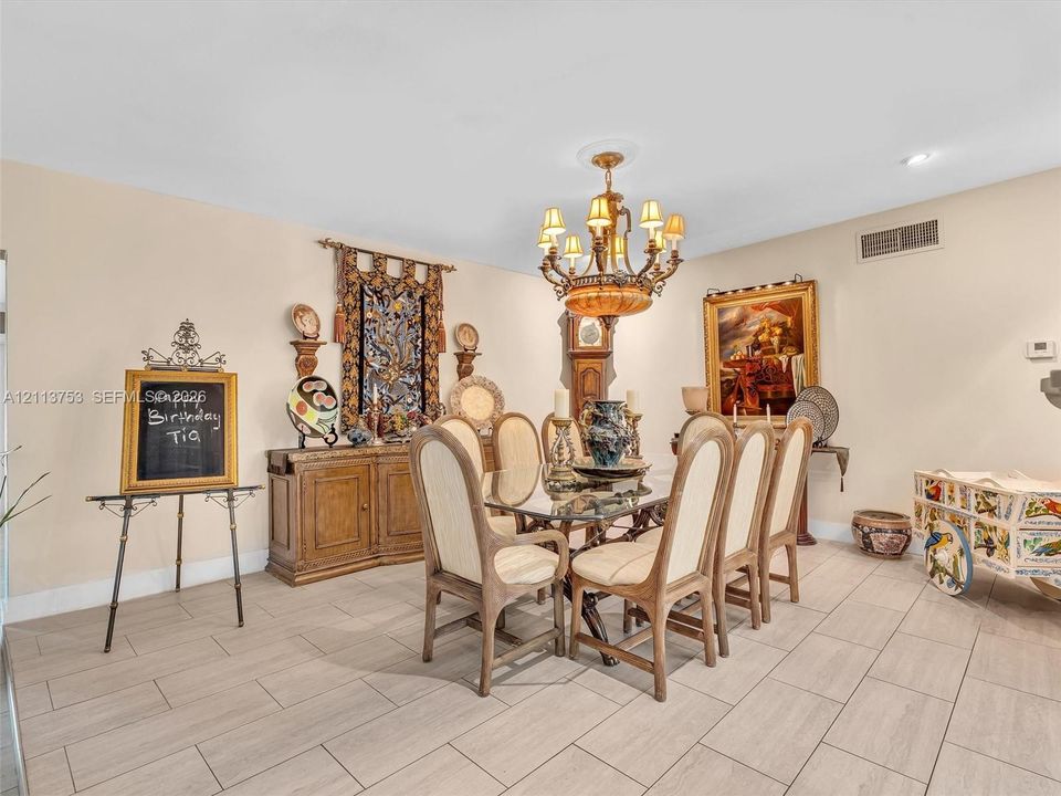 Dining space featuring large-format tile flooring and an ornate multi-tiered chandelier with warm-toned lampshades