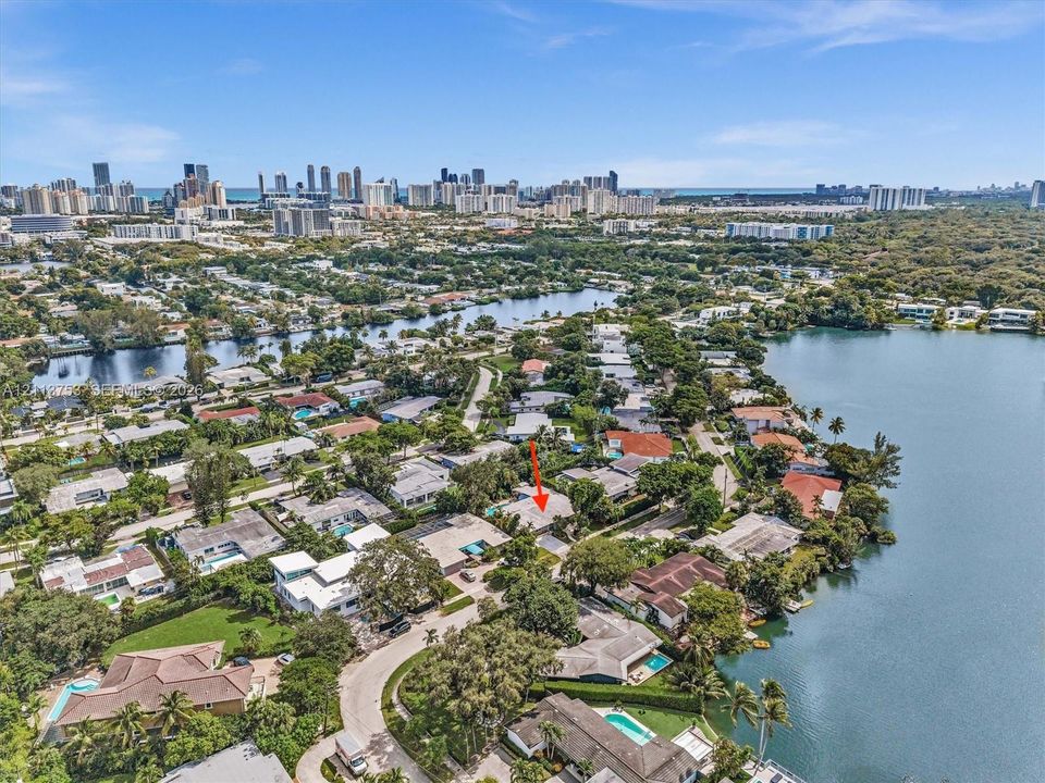 Aerial perspective of a coastal residential area featuring waterfront property proximity, mature canopy trees, and established neighborhood infrastructure