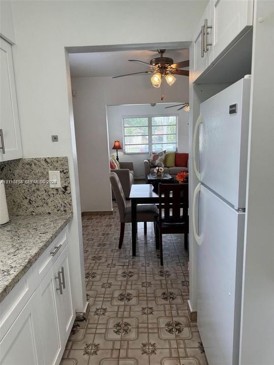 Kitchen featuring white shaker-style cabinetry, stone-surface countertops, tile flooring, and a built-in refrigerator