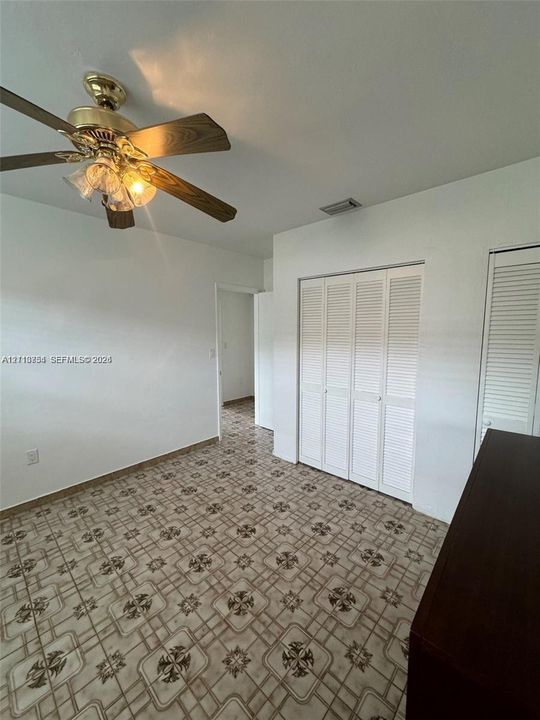 Room featuring patterned tile flooring, a multi-blade ceiling fan with integrated lighting, and white louvered closet doors
