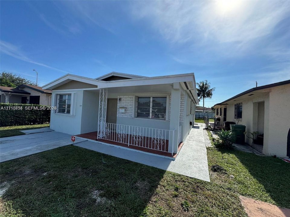 Single-story residence featuring a covered front porch, decorative wrought-iron railing, low-maintenance exterior siding, concrete walkway, and horizontal-sliding windows