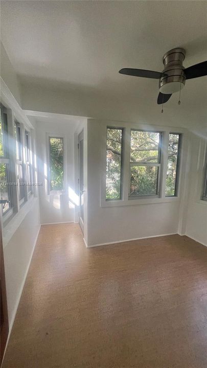 Sunroom featuring expansive windows, light-toned flooring, and a ceiling fan