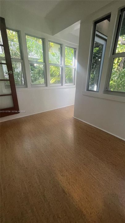 Sunroom featuring extensive windows, wood-finish flooring, and a multi-pane glass door
