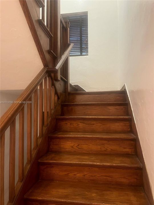 Staircase featuring natural wood treads and matching wood handrails with vertical balusters