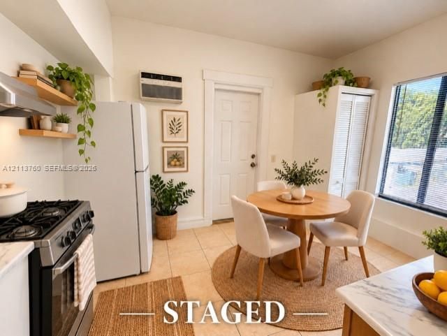 Kitchen featuring gas range, stone-finish countertops, floating wood shelves, wall-mounted air conditioning unit, and louvered-door closet