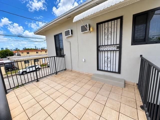 Exterior balcony featuring tiled flooring, black metal railing, and a decorative metal security door