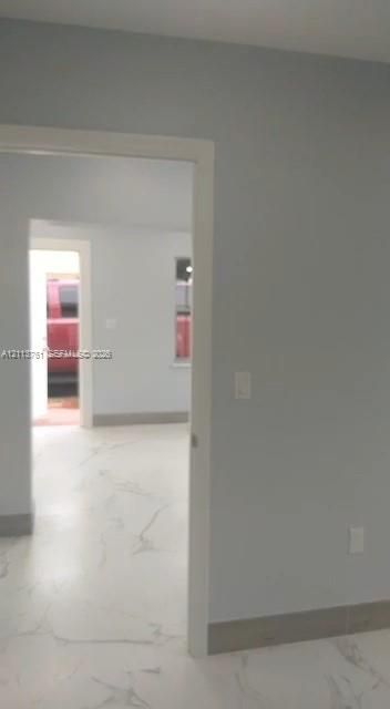 Interior featuring neutral wall paint, large-format tile flooring with veining, and crisp white door trim