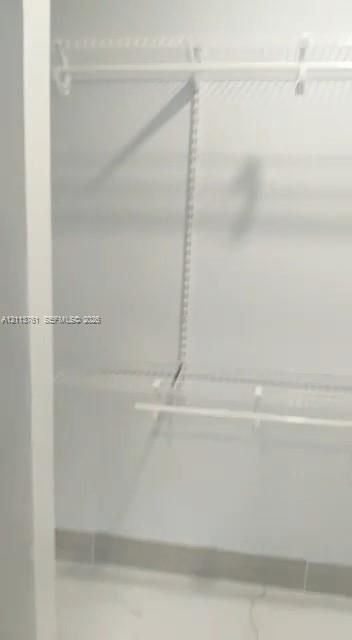 Storage area featuring white wire shelving units and wall-mounted garment rods
