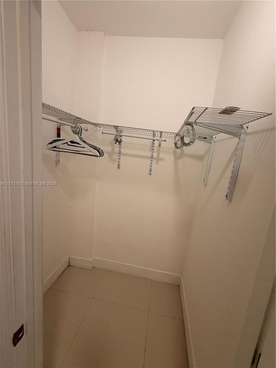 Walk-in closet featuring large-format ceramic floor tile and white-coated wire shelving systems