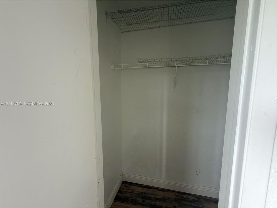 Reach-in closet featuring white walls, wood-finish flooring, and dual-level wire shelving