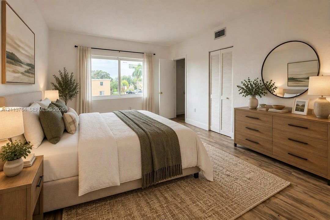 Spacious room featuring wood-finish flooring, a large window with natural light, and a double-door closet with louvered panels