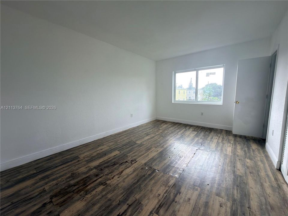Interior room featuring wood-finish flooring, white walls, and a sliding glass window
