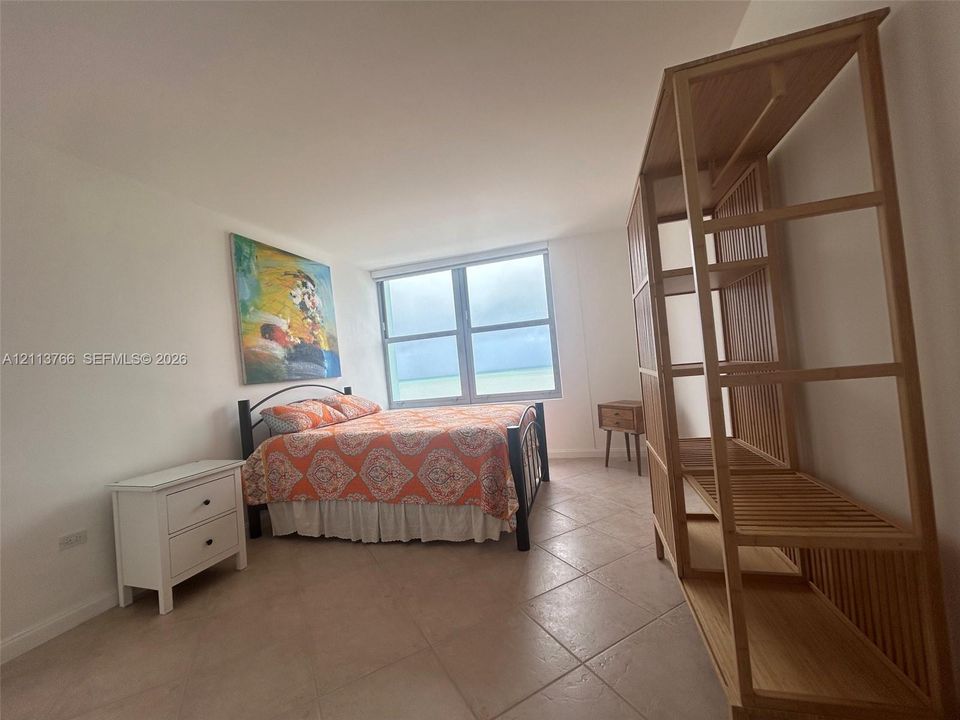 Elevated balcony with a solid perimeter wall and a direct oceanfront horizon featuring a sunset over the beach