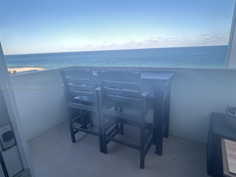 Oceanfront balcony featuring two swimming pools, paved sun deck, expansive sand beach, and tropical landscaping