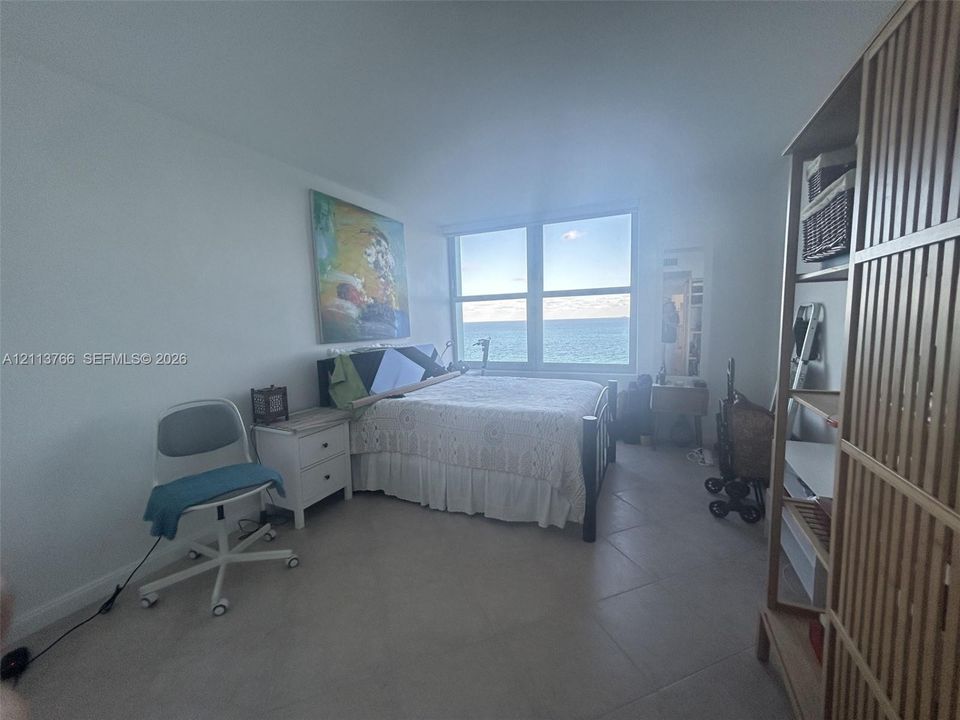 Large, high-gloss white built-in storage cabinetry, oversized horizontal window, and diagonal-set ceramic tile flooring