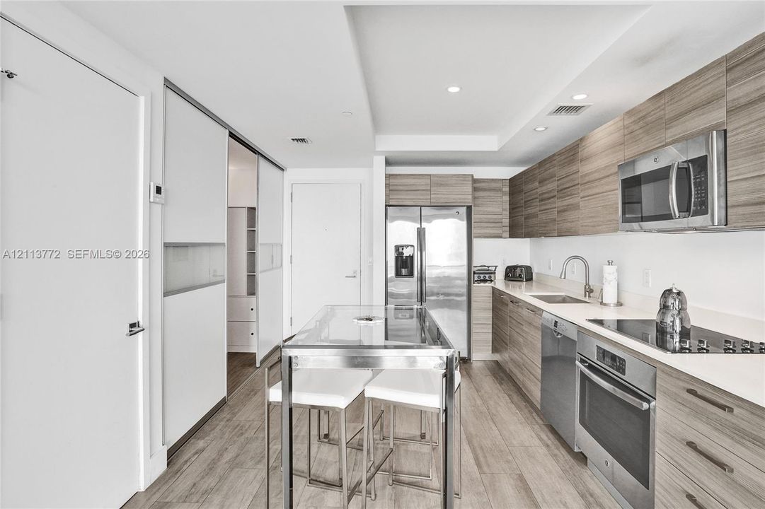 Kitchen featuring horizontal wood-grain cabinetry, stainless steel appliances, solid surface countertops, and wood-finish flooring