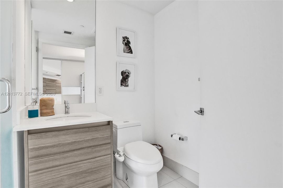 Bathroom featuring a floating wood-finish vanity, integrated white countertop with a recessed basin, chrome single-lever faucet, and large-format wall mirror