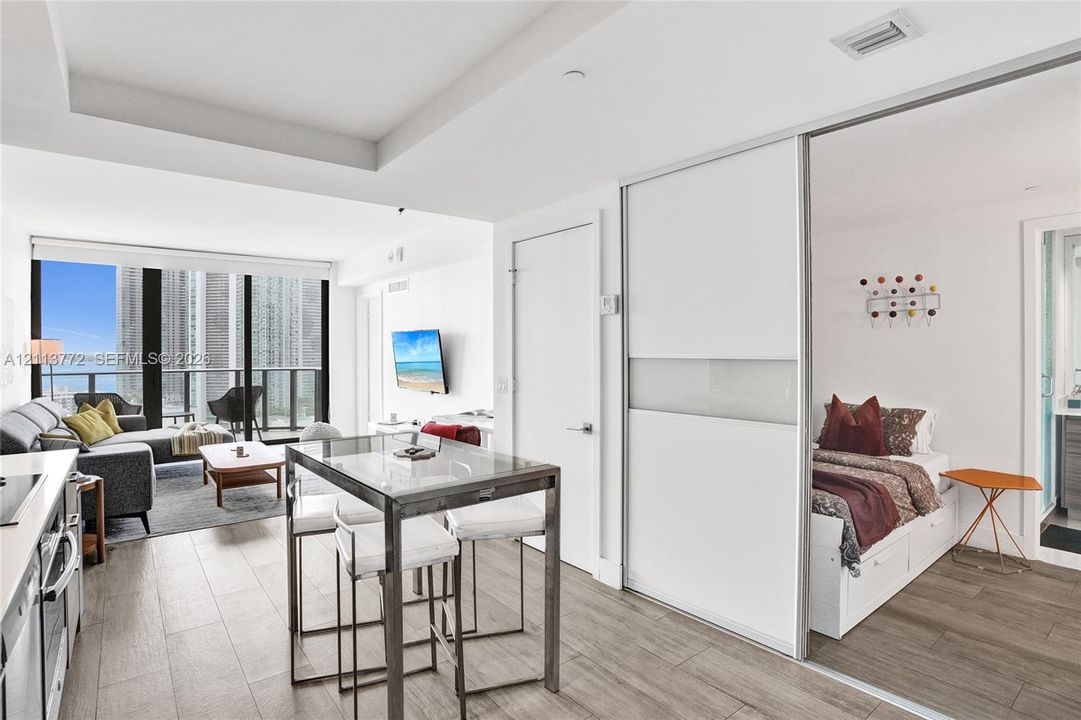 Open-concept floor plan featuring wood-finish flooring, floor-to-ceiling windows, recessed lighting, and a sliding glass door panel partition
