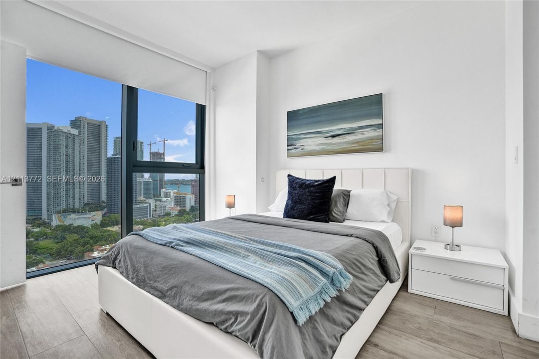 Floor-to-ceiling windows, wood-finish flooring, and high-rise cityscape scenery