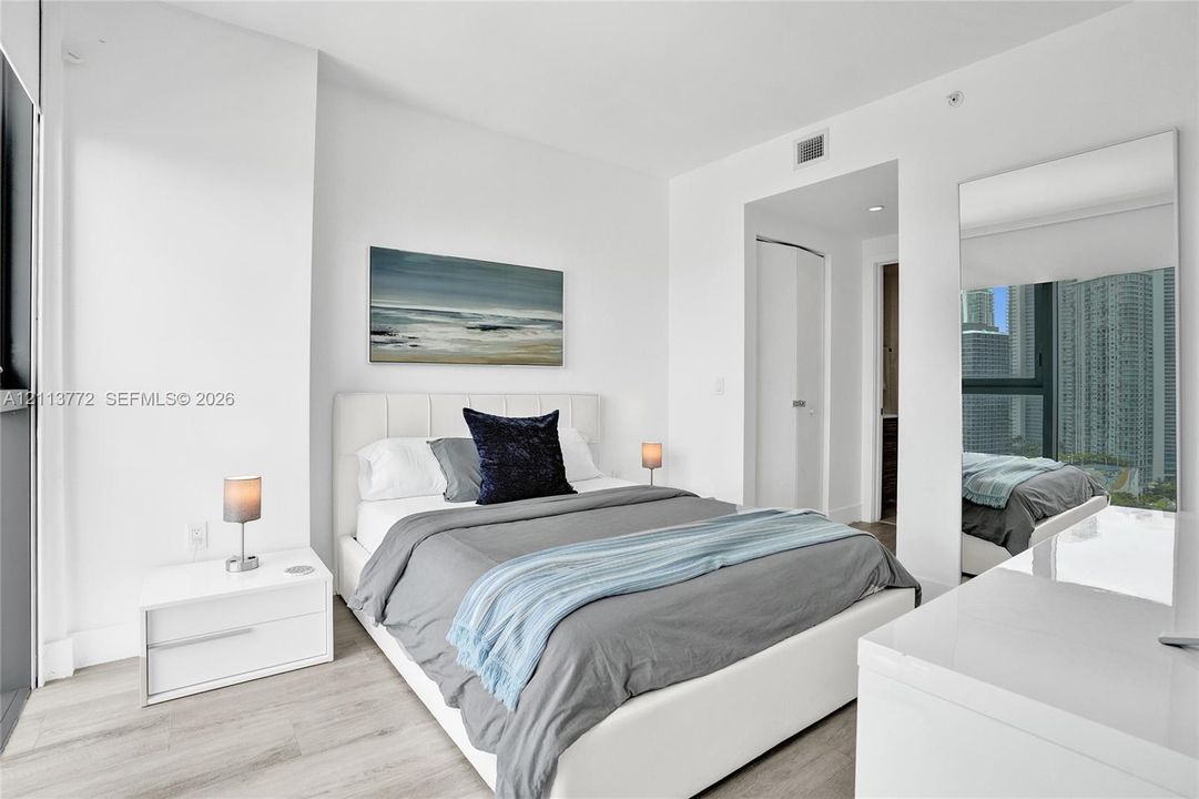 Neutral-toned wood-finish flooring, floor-to-ceiling window, and full-length wall mirror