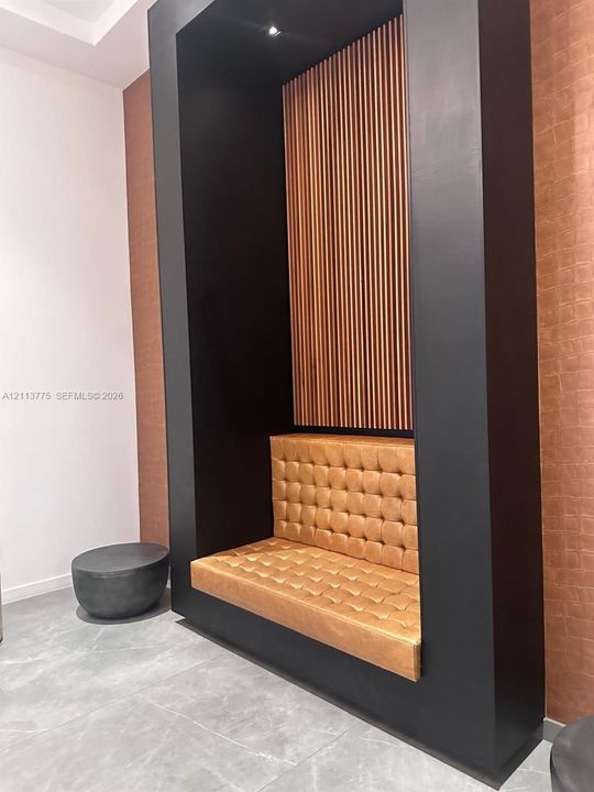 Built-in alcove featuring a matte black surround, vertical wood-slat accent paneling, and a tufted, integrated bench seat