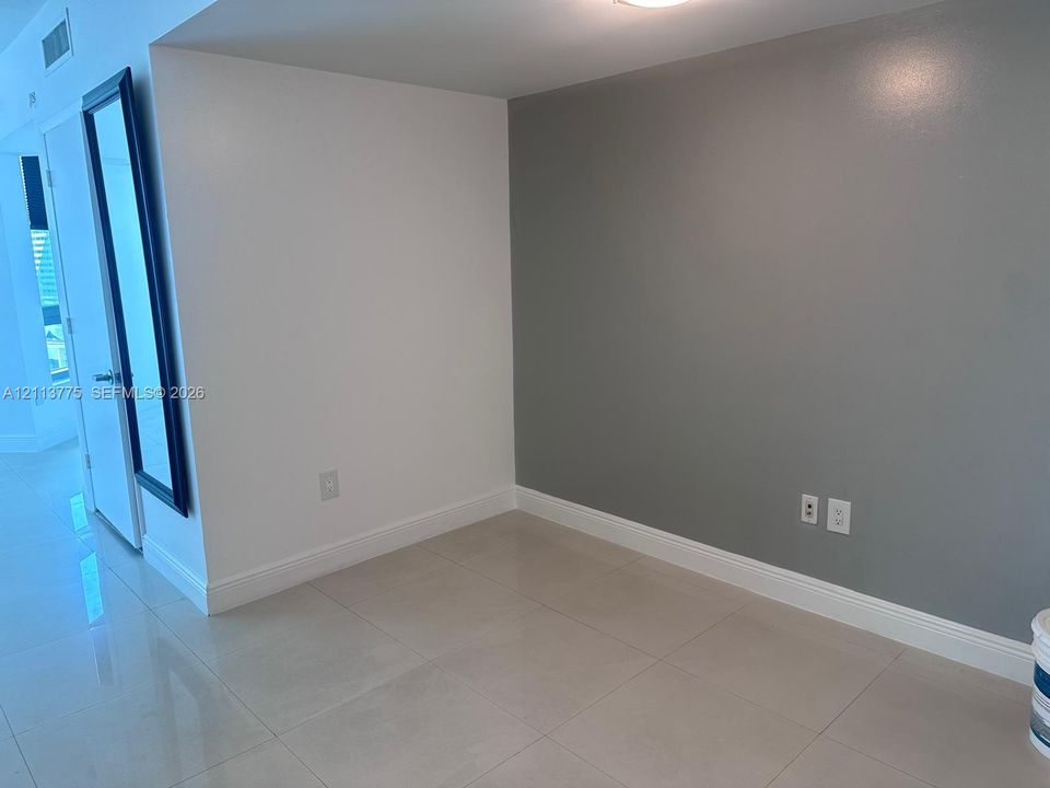 Neutral-toned interior space featuring light-colored large-format tile flooring and a contrasting grey accent wall