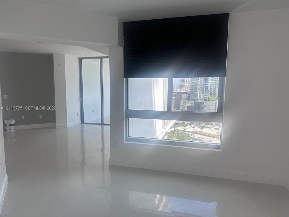 Open-concept interior featuring polished tile flooring, floor-to-ceiling windows, and sliding glass doors