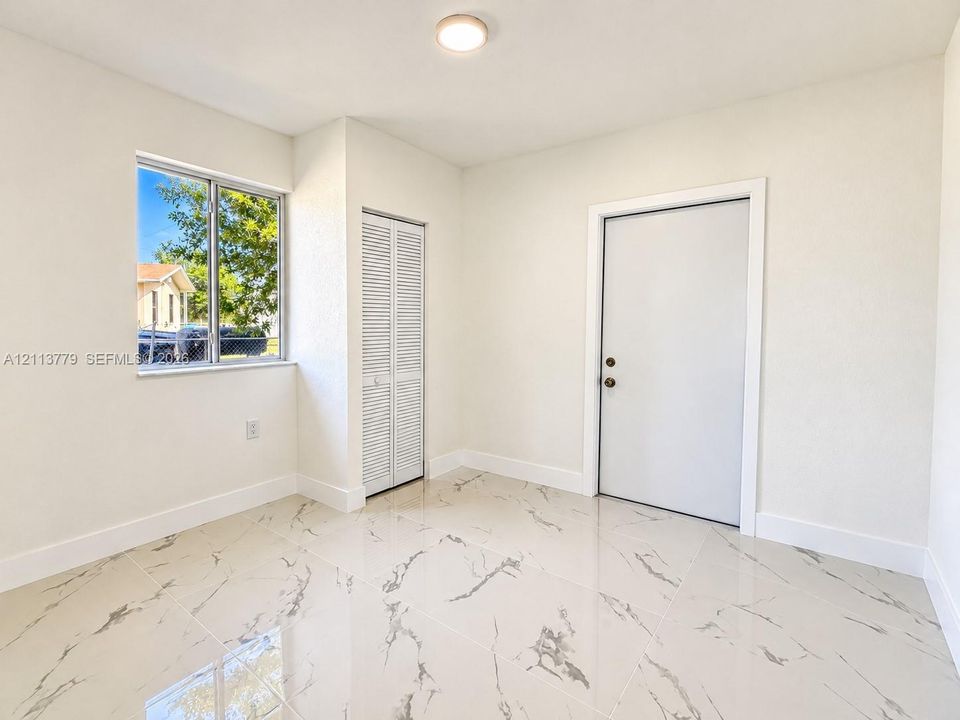 Polished tile flooring with high-contrast veining, dual-pane window, bifold closet door, and interior flush-panel door