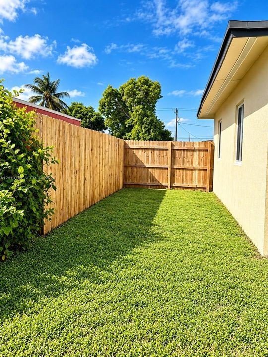 Side yard featuring a manicured lawn, wood privacy fencing, and exterior stucco siding