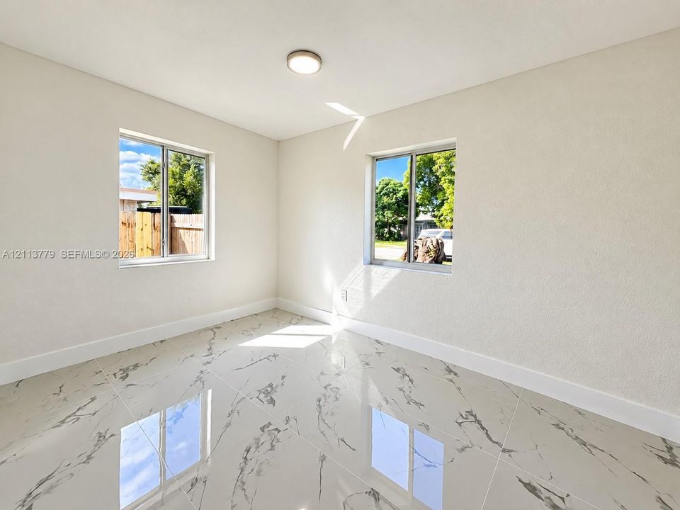 Glossy stone-patterned tile flooring, neutral walls, and dual sliding windows with integrated framing