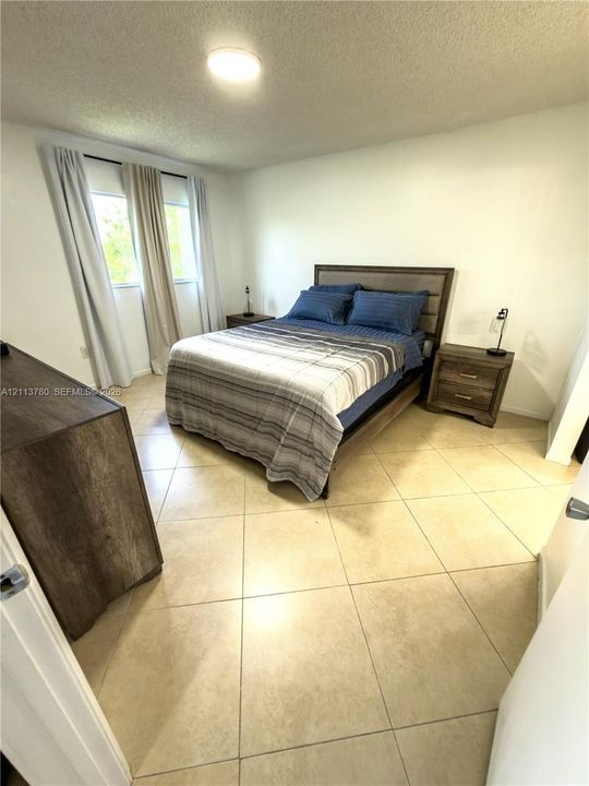 Large-format tile flooring, textured ceiling finish, and dual-pane windows with integrated track lighting