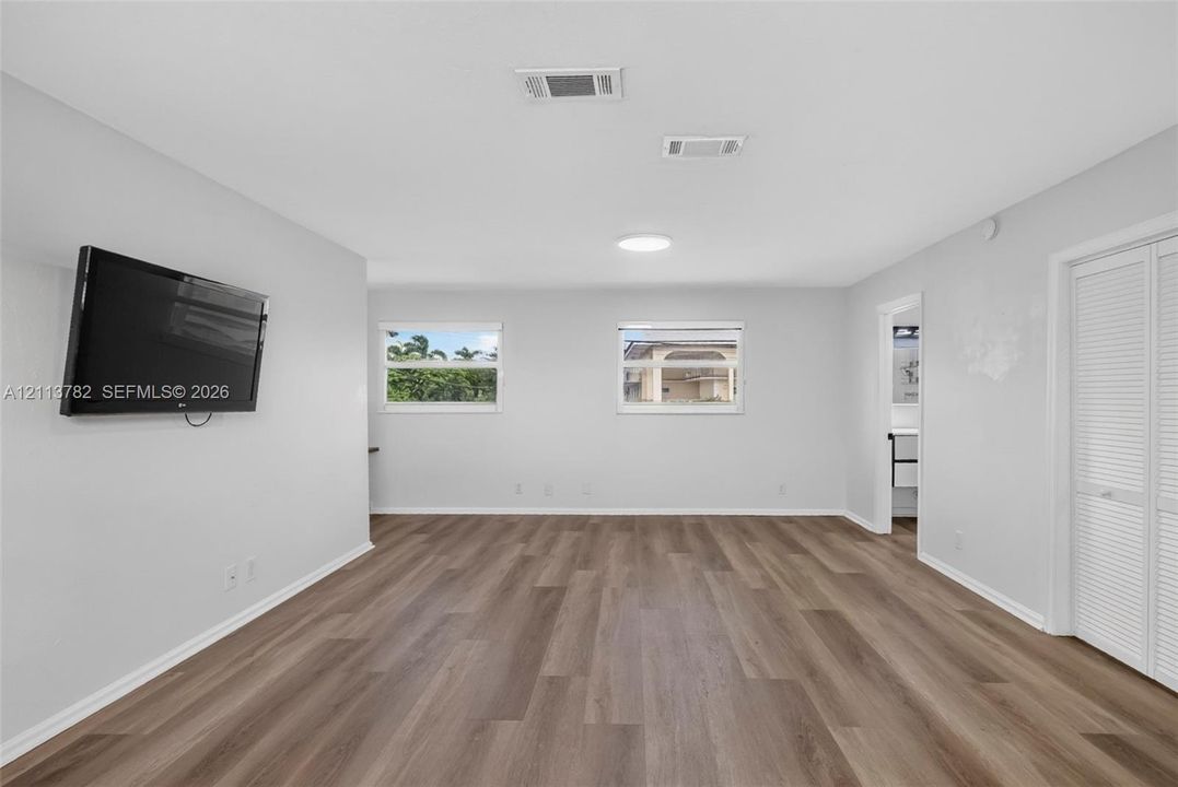 Neutral interior featuring wood-finish flooring, two dual-pane windows, and white bifold closet doors