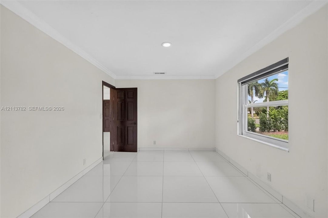 Interior space featuring large-format tile flooring, crown molding, recessed lighting, and a multi-panel wood door