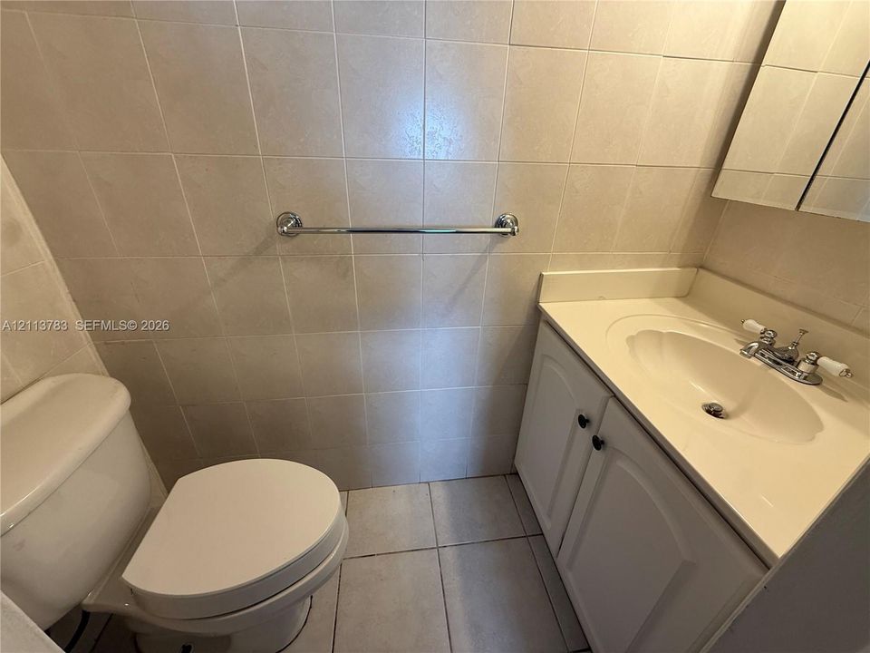 Room featuring light-colored tile flooring, mirrored sliding closet doors, and a rectangular window