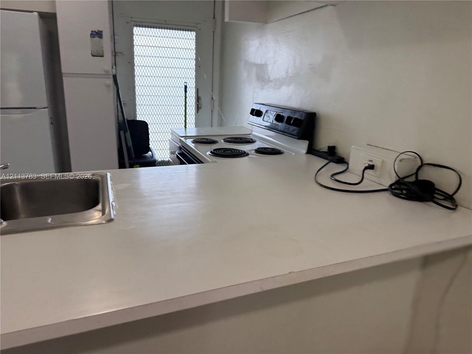 Kitchen pass-through featuring a laminate countertop, dual-basin stainless steel sink, tile flooring, and a decorative stained glass pendant light fixture