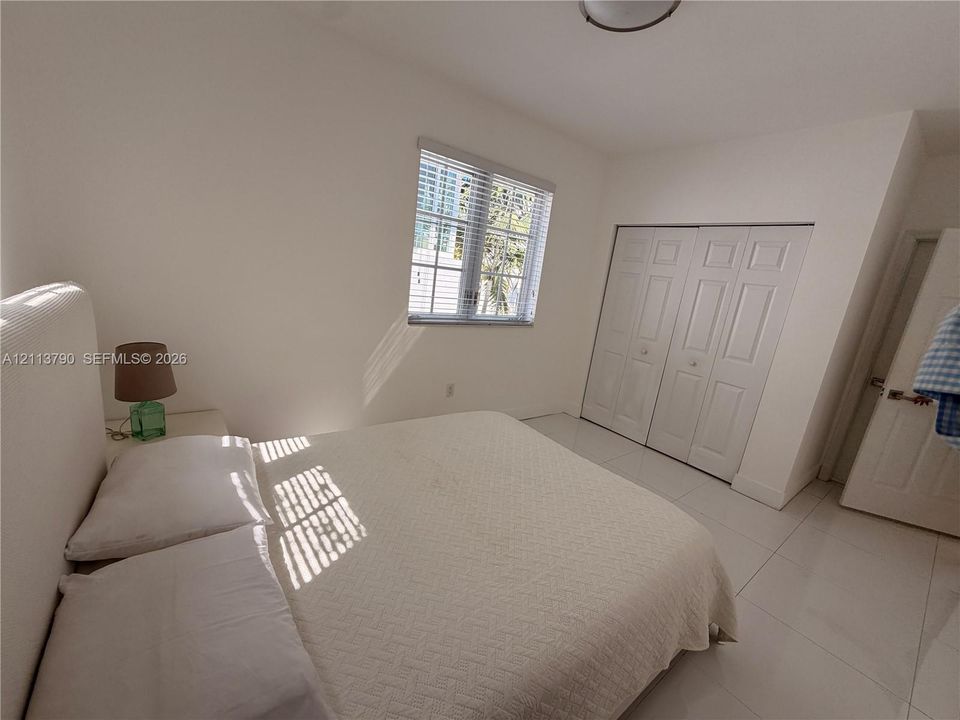 Neutral-toned interior featuring large-format tile flooring, a multi-panel window with grid detailing, and a closet with bifold doors