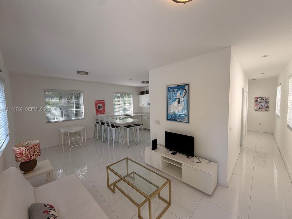 Open-concept interior featuring large-format tile flooring, recessed lighting, and a kitchen island with stone-surface countertop and bar seating