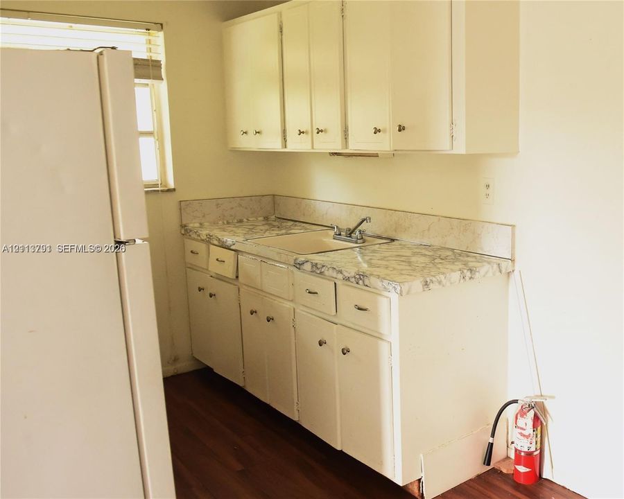 Kitchen featuring white cabinetry, patterned laminate countertops, a dual-basin sink with a metallic faucet, and wood-finish flooring