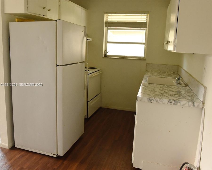 Kitchen featuring white cabinetry, patterned laminate countertops, a single-basin sink, wood-finish flooring, and a window