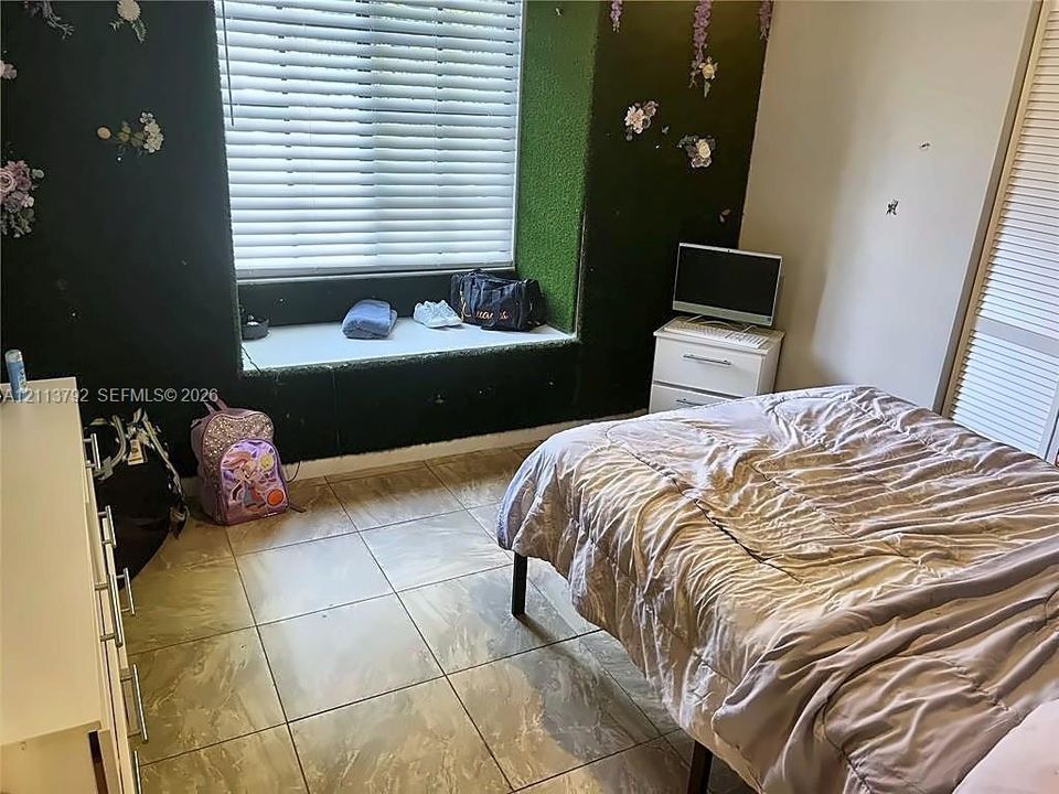 Large-format tile flooring, recessed window seat, and built-in closet with louvred doors
