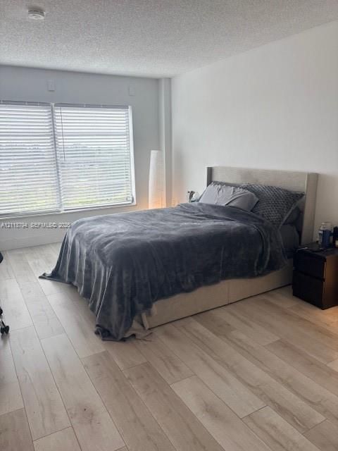 Light-toned wood-finish flooring, neutral walls, and large horizontal window blinds
