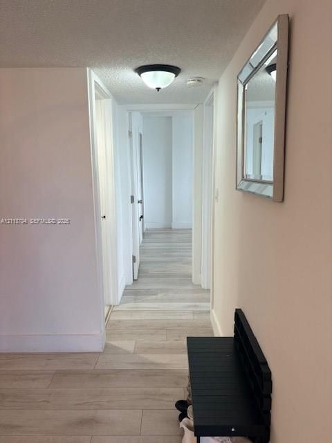 Hallway featuring wood-finish flooring, neutral wall tones, and a flush-mount ceiling light fixture