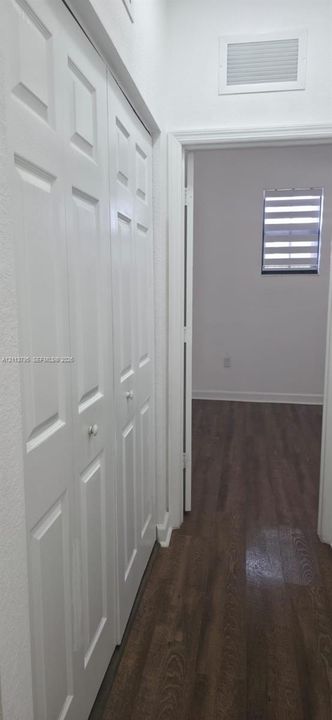 White bi-fold closet doors, wood-finish flooring, and horizontal-blind window treatment