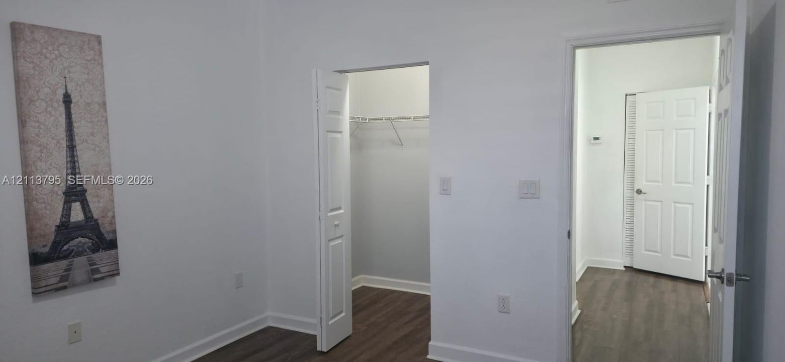 Interior space featuring wood-finish flooring, a built-in closet with shelving, and a six-panel interior door