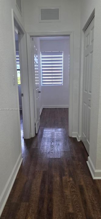 Hallway featuring wood-finish flooring, white door casings, and paneled doors