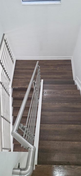 Staircase featuring wood-finish treads and a modern brushed-metal horizontal railing system